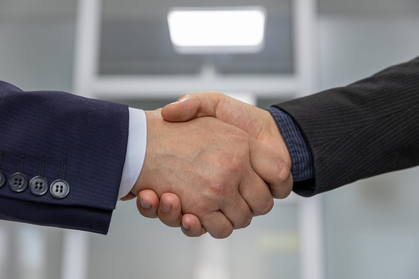 Two people shaking hands over a signed business document, representing a franchise or conversion agreement.
