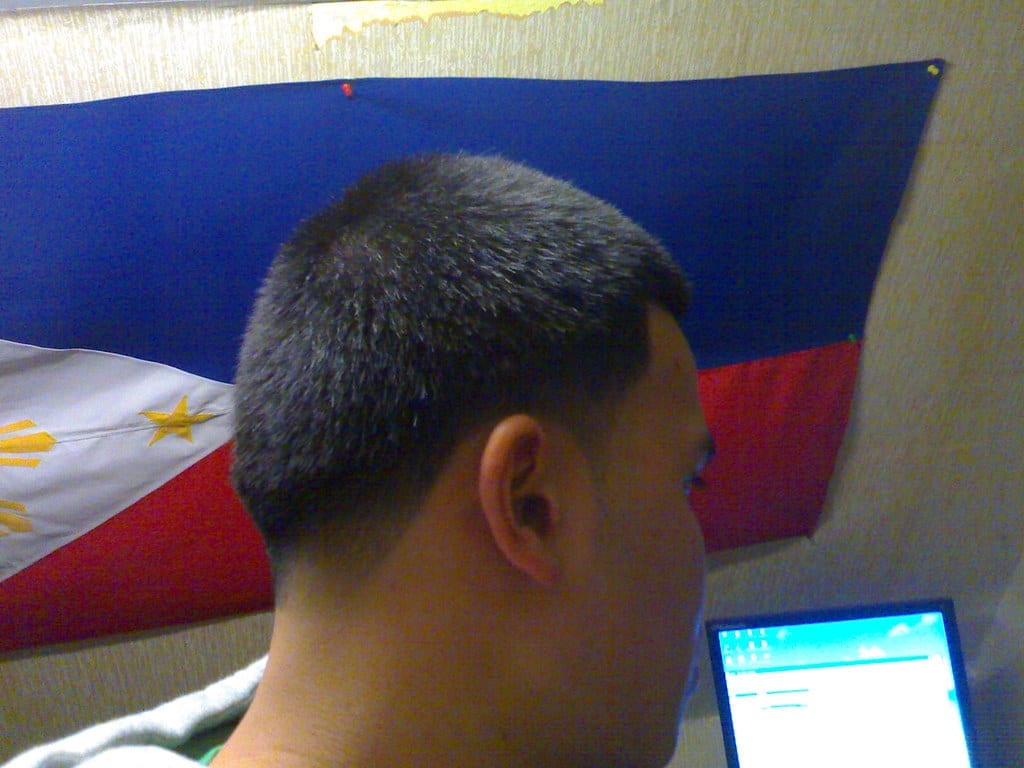 Barber giving a client a haircut with clippers, close-up on the tapered cut