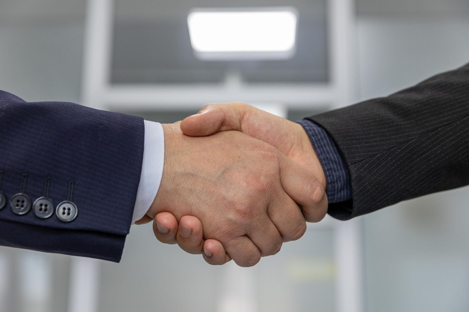Two people shaking hands over a signed business agreement