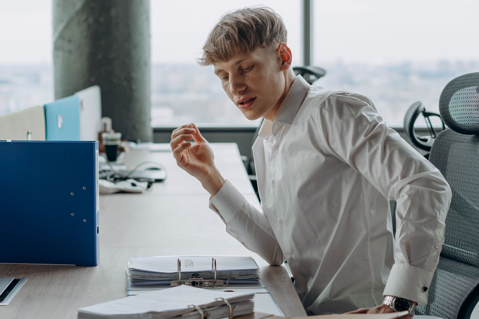 A person at a desk reading through a thick bound set of documents