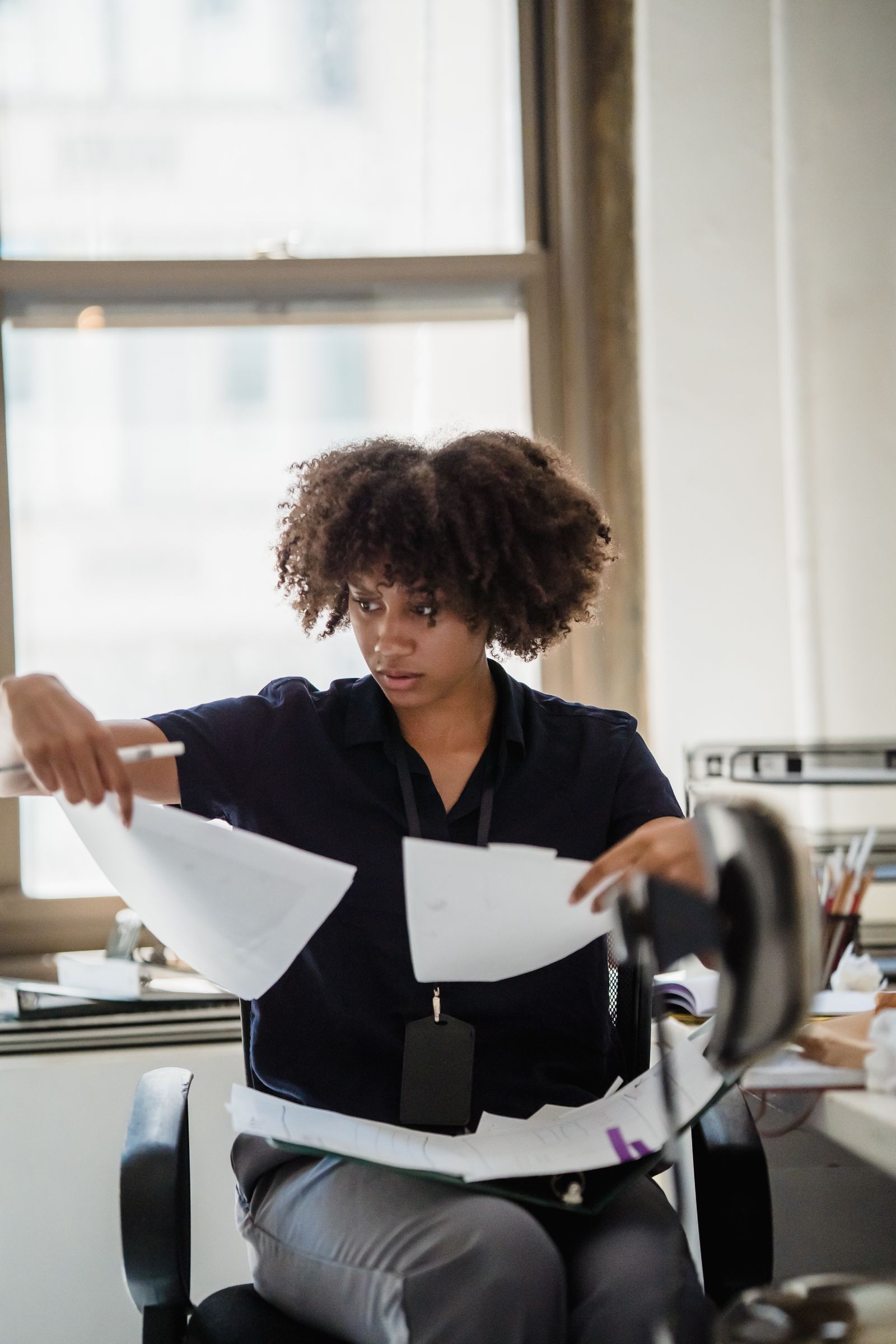 A person sorting through two sheets of paper, comparing them side by side at a desk