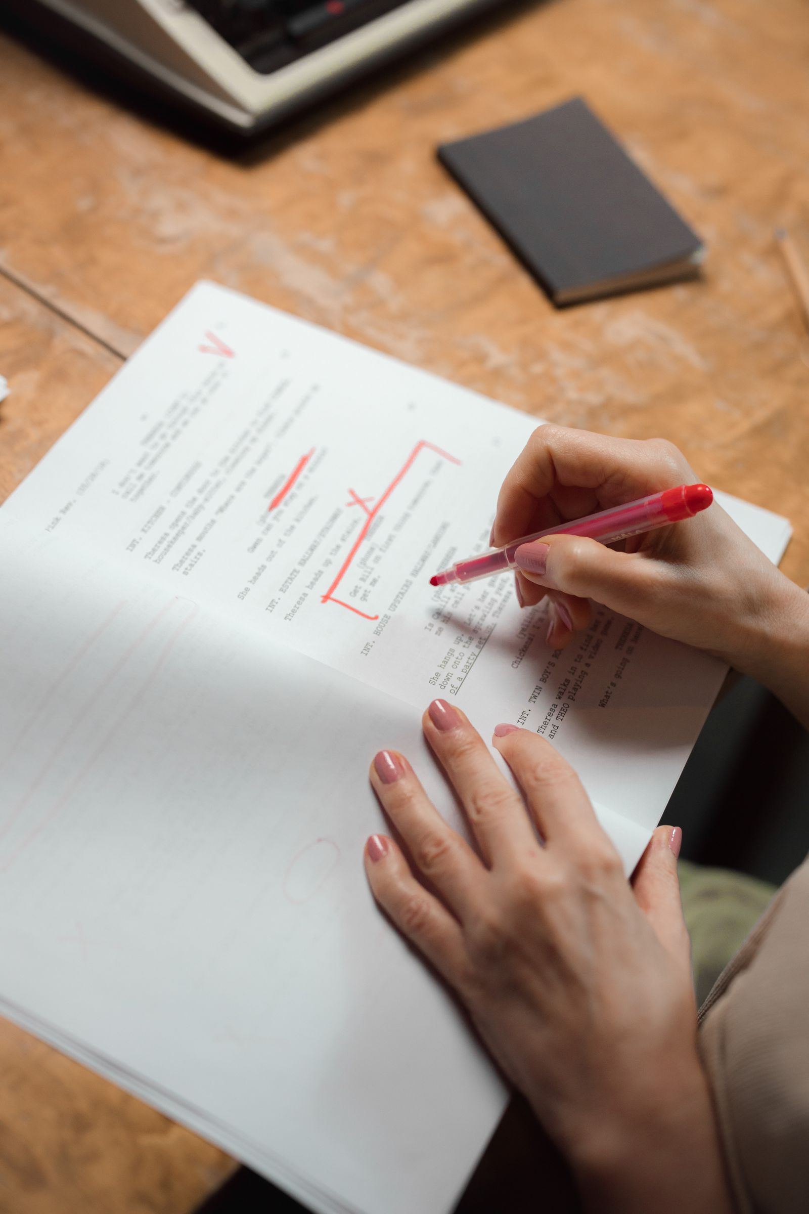 A hand marking corrections on a printed page with a red pen