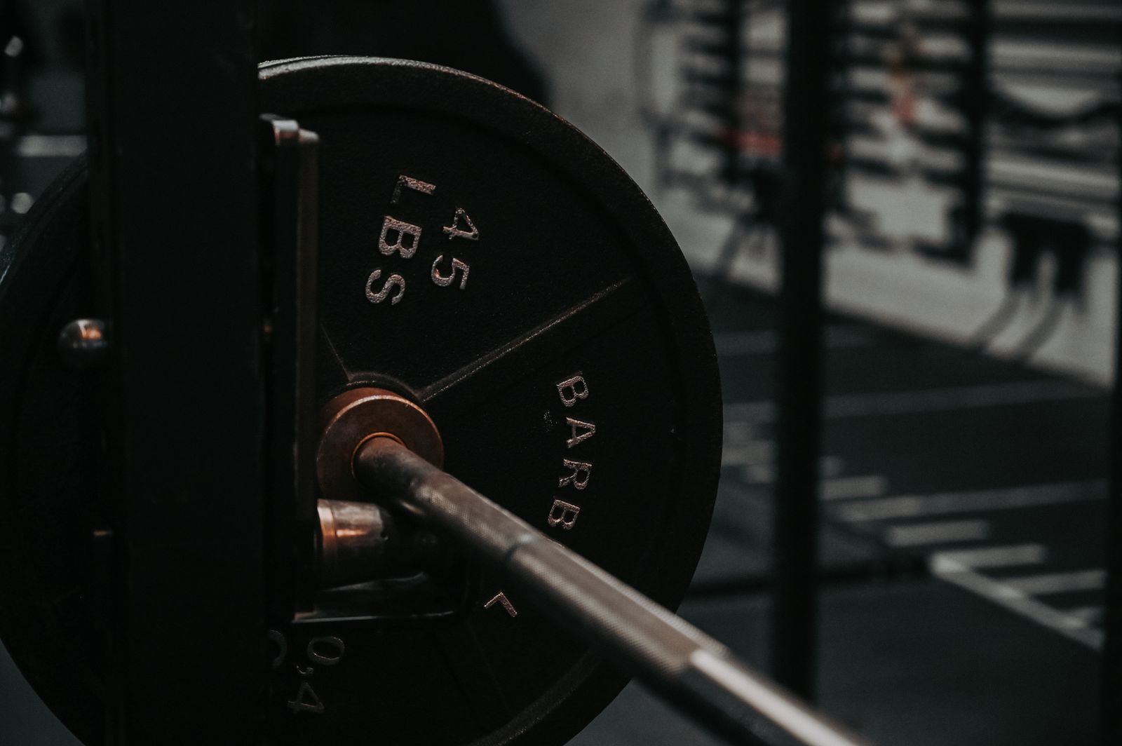 A close-up of a loaded 45-pound barbell plate racked in a dimly lit gym